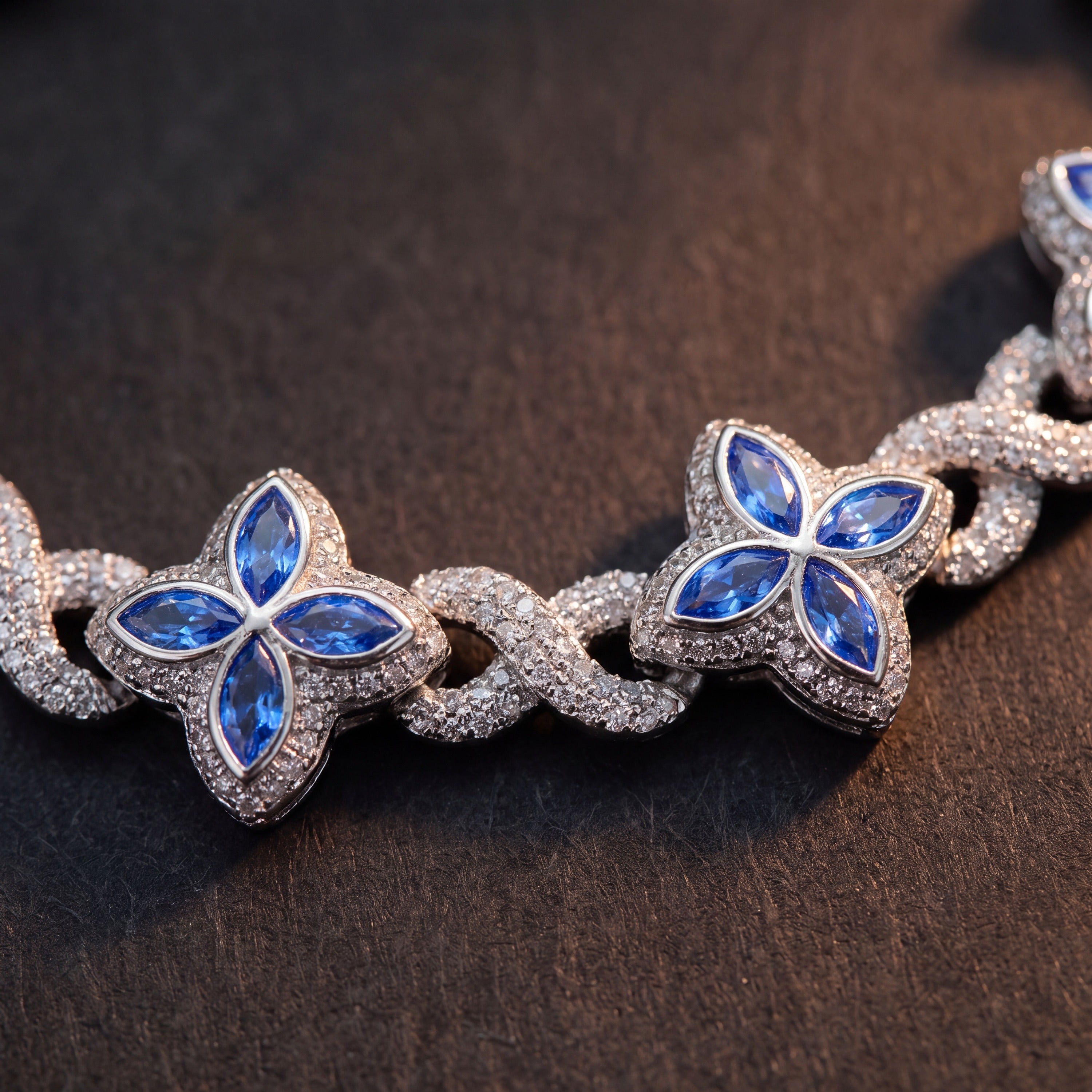 Close-up of blue marquise-petal flowers between pave infinity links in silver tone